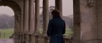 Movie still from “The Young Victoria” (2009), directed by Jean-Marc Vallée – A woman standing in front of pillars looking out on a cloudy day; Medium shot, Over the shoulder angle