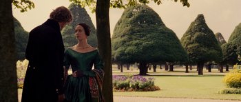 Movie still from “The Young Victoria” (2009), directed by Jean-Marc Vallée – A woman in a green dress standing next to a tree in a park; Medium shot, Over the shoulder angle