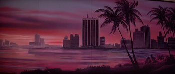 Movie still from “Scarface” (1983), directed by Brian De Palma – A painting of a palm tree in front of a city skyline; Extreme Wide shot, Low angle