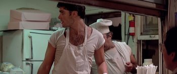 Movie still from “Scarface” (1983), directed by Brian De Palma – A man wearing an apron while standing next to another man wearing an apron; Close Up shot, Over the shoulder angle