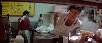 Movie still from “Scarface” (1983), directed by Brian De Palma – A man standing in front of a counter in a kitchen; Medium shot, Low angle