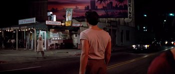 Movie still from “Scarface” (1983), directed by Brian De Palma – A man standing on the side of the road at night; Wide shot, Low angle