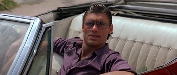 Movie still from “Scarface” (1983), directed by Brian De Palma – A person wearing a purple shirt; Close Up shot, Low angle