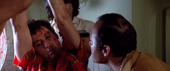 Movie still from “Scarface” (1983), directed by Brian De Palma – A man is getting his hair cut by another man; Close Up shot, Low angle