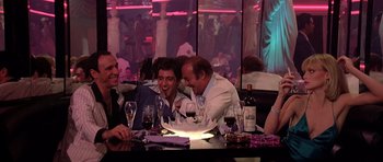 Movie still from “Scarface” (1983), directed by Brian De Palma – A group of men sitting at a table with wine glasses; Wide shot, Over the shoulder angle