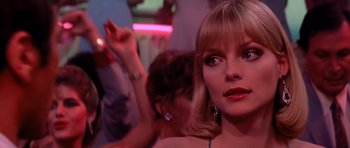 Movie still from “Scarface” (1983), directed by Brian De Palma – A woman in a red dress is in a bar; Close Up shot, Over the shoulder angle