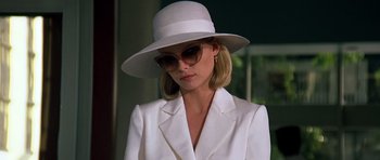 Movie still from “Scarface” (1983), directed by Brian De Palma – A woman in a white suit and a white hat; Close Up shot, Low angle