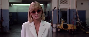 Movie still from “Scarface” (1983), directed by Brian De Palma – A woman wearing a white suit and sunglasses; Medium shot, Low angle