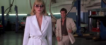 Movie still from “Scarface” (1983), directed by Brian De Palma – A man and a woman in a white suit and sunglasses; Medium shot, Low angle