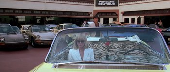 Movie still from “Scarface” (1983), directed by Brian De Palma – A woman sitting in the back seat of a car; Wide shot, Over the shoulder angle