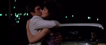 Movie still from “Scarface” (1983), directed by Brian De Palma – A man and a woman kissing each other in the dark; Close Up shot, Low angle