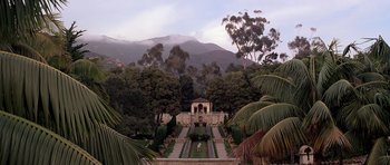 Movie still from “Scarface” (1983), directed by Brian De Palma – A garden with a fountain and a gazebo in front of a mountain range; Extreme Wide shot, High angle