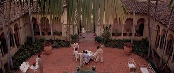 Movie still from “Scarface” (1983), directed by Brian De Palma – A group of people standing around a table; Extreme Wide shot, High angle
