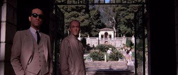 Movie still from “Scarface” (1983), directed by Brian De Palma – A man standing in front of a garden with a gazebo in the background; Medium shot, Low angle