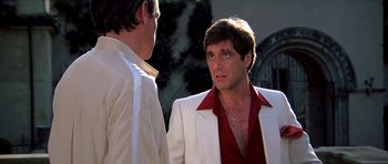 Movie still from “Scarface” (1983), directed by Brian De Palma – A man in a white jacket and a man in a red shirt; Close Up shot, Over the shoulder angle