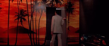 Movie still from “Scarface” (1983), directed by Brian De Palma – A man in a suit standing in front of a door; Wide shot, Low angle