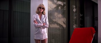 Movie still from “Scarface” (1983), directed by Brian De Palma – A woman in a white suit standing in front of a window; Medium shot, Low angle