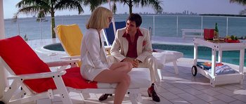 Movie still from “Scarface” (1983), directed by Brian De Palma – A man and a woman are sitting on a chair by the water; Wide shot, Low angle