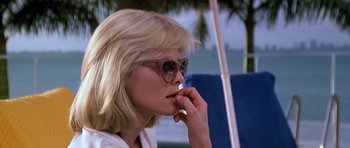 Movie still from “Scarface” (1983), directed by Brian De Palma – A woman wearing sunglasses and a white shirt; Close Up shot, Low angle