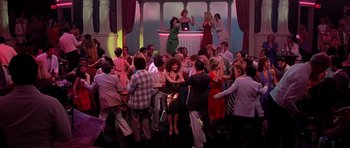 Movie still from “Scarface” (1983), directed by Brian De Palma – A group of people standing in a room; Extreme Wide shot, High angle