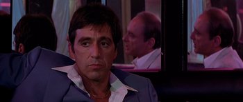 Movie still from “Scarface” (1983), directed by Brian De Palma – Al pacino wearing a suit and tie; Close Up shot, Over the shoulder angle