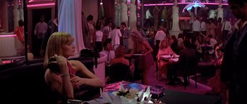 Movie still from “Scarface” (1983), directed by Brian De Palma – A group of people are gathered around a table; Wide shot, Over the shoulder angle