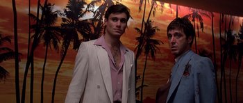 Movie still from “Scarface” (1983), directed by Brian De Palma – A man in a suit and tie standing next to another man; Medium shot, Low angle