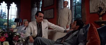 Movie still from “Scarface” (1983), directed by Brian De Palma – A group of men sitting on top of a white couch; Medium shot, Low angle