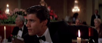 Movie still from “Scarface” (1983), directed by Brian De Palma – A man in a suit and bow tie looking up at something; Close Up shot, Over the shoulder angle