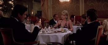 Movie still from “Scarface” (1983), directed by Brian De Palma – A woman sitting at a table with a glass of wine; Medium shot, Over the shoulder angle