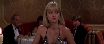 Movie still from “Scarface” (1983), directed by Brian De Palma – A woman in a sequined top sitting at a dinner table; Close Up shot, Low angle