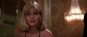 Movie still from “Scarface” (1983), directed by Brian De Palma – A woman with blonde hair wearing a black bikini top; Close Up shot, Over the shoulder angle