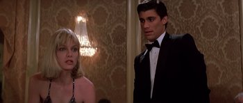 Movie still from “Scarface” (1983), directed by Brian De Palma – A man and a woman standing next to each other in formal wear; Medium shot, Low angle