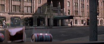 Movie still from “Scarface” (1983), directed by Brian De Palma – A man standing on the side of the road near a tall building; Wide shot, High angle