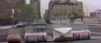 Movie still from “Scarface” (1983), directed by Brian De Palma – Cars driving down a city street in the daytime; Wide shot, High angle