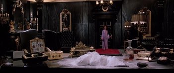 Movie still from “Scarface” (1983), directed by Brian De Palma – A woman in a purple robe standing in front of a bed; Wide shot, High angle