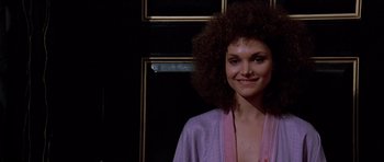 Movie still from “Scarface” (1983), directed by Brian De Palma – A woman in a purple robe smiling for the camera; Close Up shot, Low angle