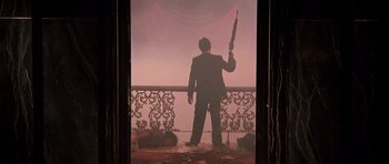 Movie still from “Scarface” (1983), directed by Brian De Palma – A man in a black suit holding a black umbrella; Wide shot, Low angle