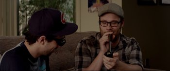 Movie still from “This Is the End” (2013), directed by Seth Rogen – Two men sitting on a couch looking at a cell phone; Medium shot, Overhead angle