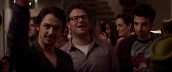 Movie still from “This Is the End” (2013), directed by Seth Rogen – A group of men and women standing next to each other in a room; Medium shot, Over the shoulder angle