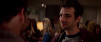 Movie still from “This Is the End” (2013), directed by Seth Rogen – A person smiling at a party; Close Up shot, Over the shoulder angle