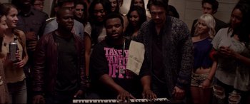 Movie still from “This Is the End” (2013), directed by Seth Rogen – A group of people standing around a man playing a piano; Medium shot, High angle