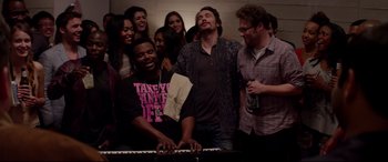 Movie still from “This Is the End” (2013), directed by Seth Rogen – A group of people standing next to each other and a piano; Medium shot, High angle