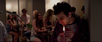 Movie still from “This Is the End” (2013), directed by Seth Rogen – A young man holding a lit cigarette in his mouth; Medium shot, Over the shoulder angle