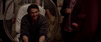 Movie still from “This Is the End” (2013), directed by Seth Rogen – A man sitting next to another man holding a drink; Medium shot, High angle