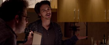 Movie still from “This Is the End” (2013), directed by Seth Rogen – A young man in a black shirt is holding papers; Medium shot, Over the shoulder angle