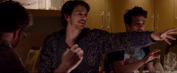 Movie still from “This Is the End” (2013), directed by Seth Rogen – A man sitting at a table with a drink in front of him; Medium shot, Over the shoulder angle