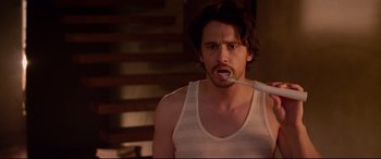 Movie still from “This Is the End” (2013), directed by Seth Rogen – A young man brushing his teeth with an electric toothbrush; Medium shot, Over the shoulder angle