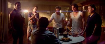 Movie still from “This Is the End” (2013), directed by Seth Rogen – A group of people standing around a table; Medium shot, Over the shoulder angle