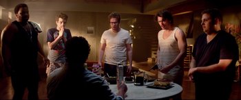 Movie still from “This Is the End” (2013), directed by Seth Rogen – A group of people standing around a table; Medium shot, Over the shoulder angle